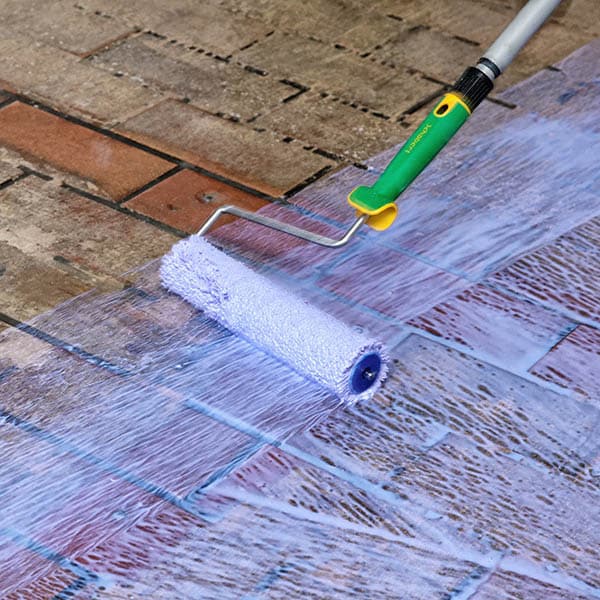 Handwerker trägt Bodenbeschichtung mit einer Rolle auf, Heer & Werz Baustoffhandel